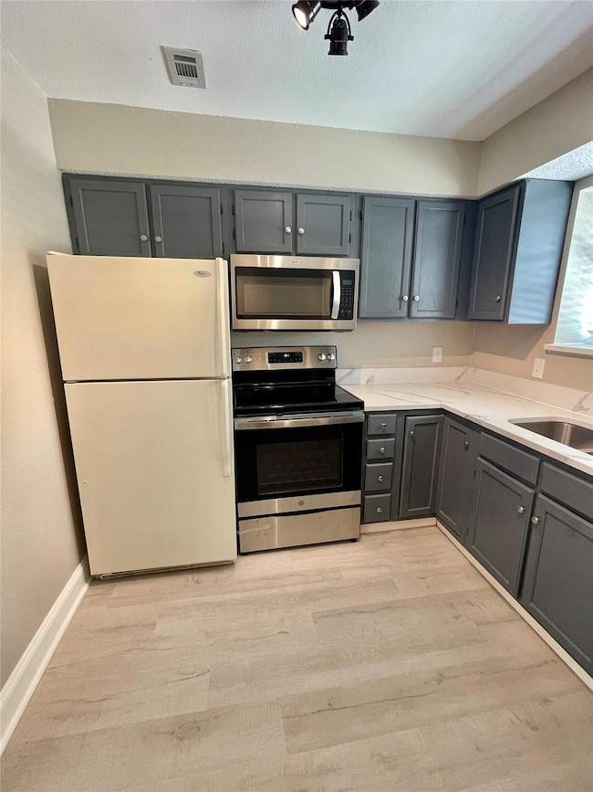 Kitchen featuring gray cabinets, sink, appliances 