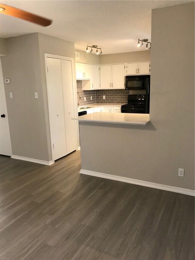 Kitchen with white cabinets, decorative backsplash, dark wood-style floors, light countertops, and a textured ceiling