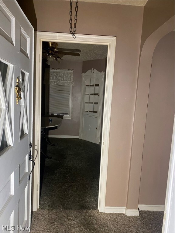 Hallway featuring dark colored carpet