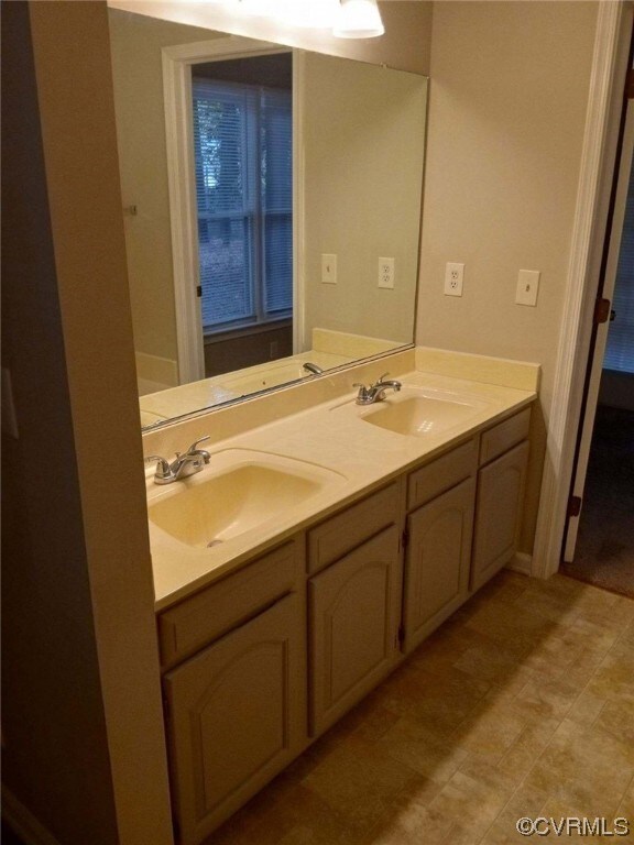 Bathroom with large vanity, tile floors, and dual sinks