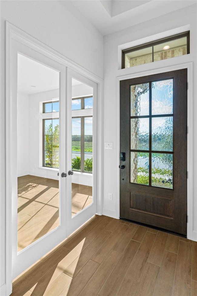 Foyer entrance with wood finished floors and fren