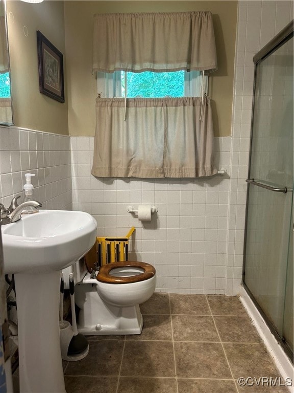 Bathroom with tile walls, a stall shower, toilet,