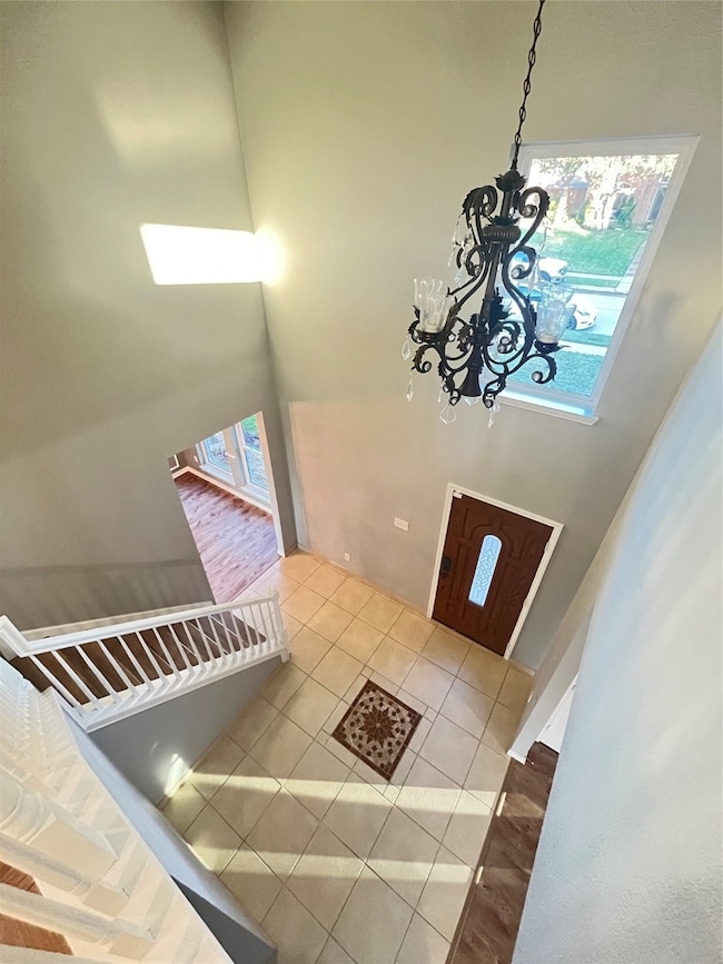Tiled entrance foyer featuring a towering ceiling and a chandelier