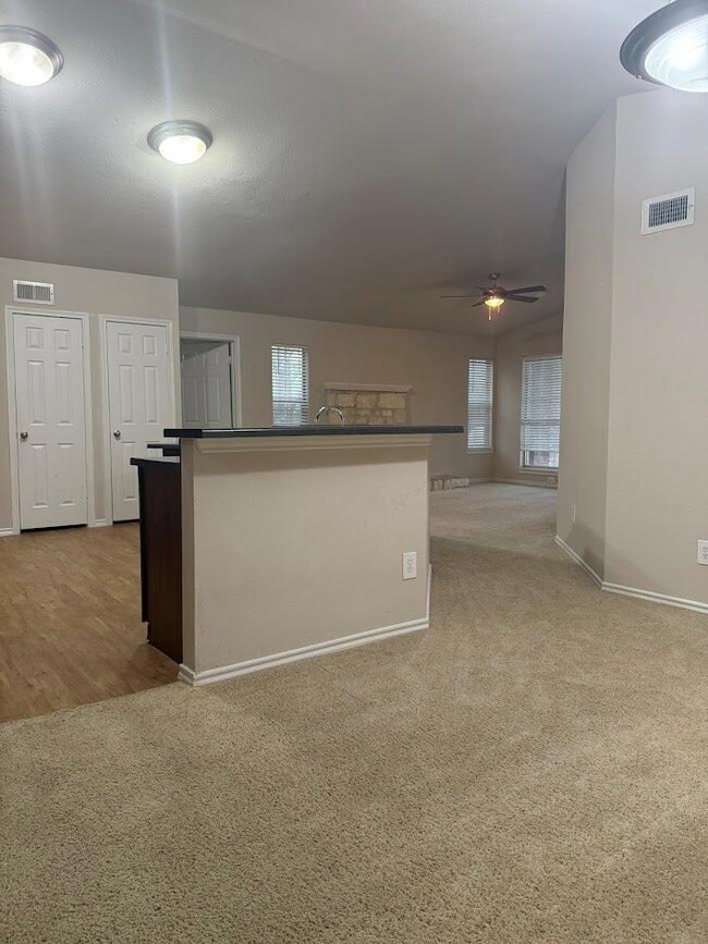 Kitchen with carpet floors, a ceiling fan, and a kitchen island with sink