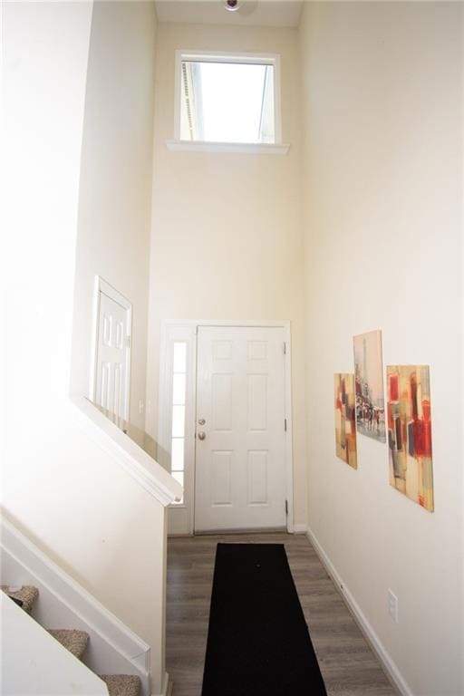 Foyer entrance featuring wood finished floors, a high ceiling, and stairs