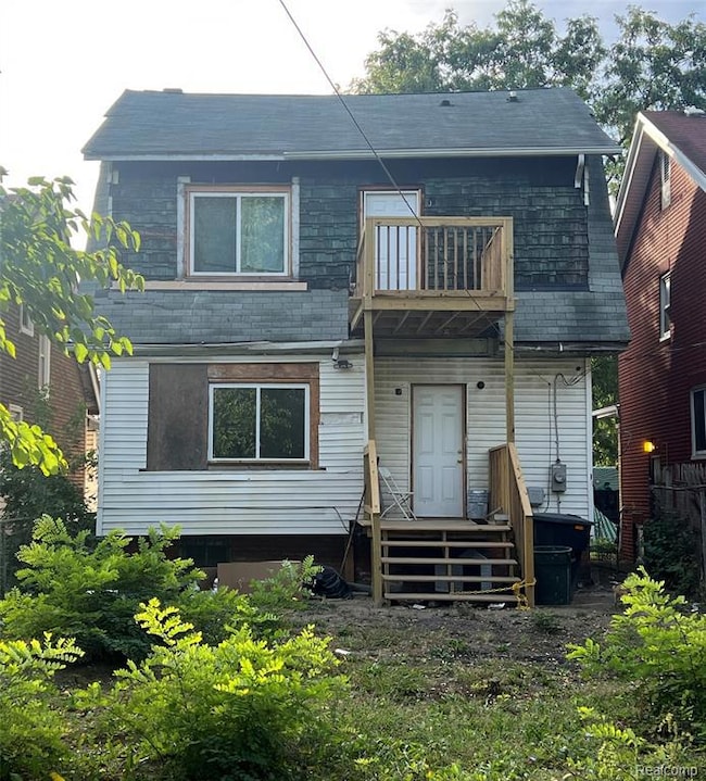 Rear view of house with a balcony and roof with shingles