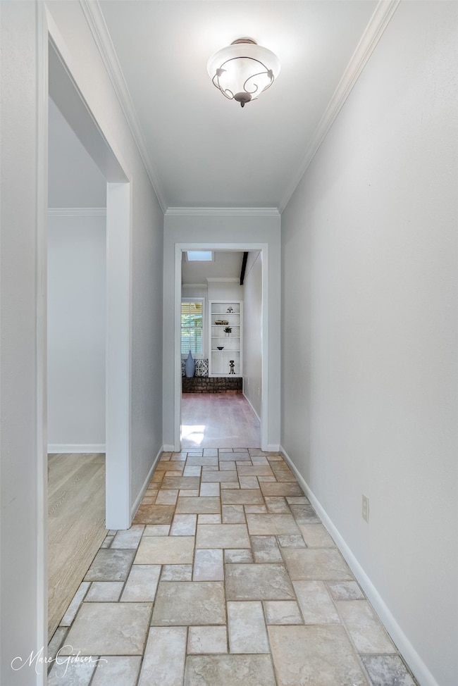 Corridor featuring light stone finish floors and crown molding