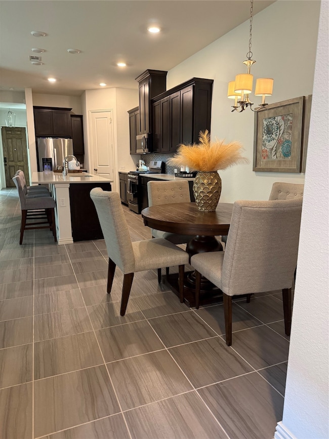 Dining space with a chandelier, light tile patterned floors, and recessed lighting