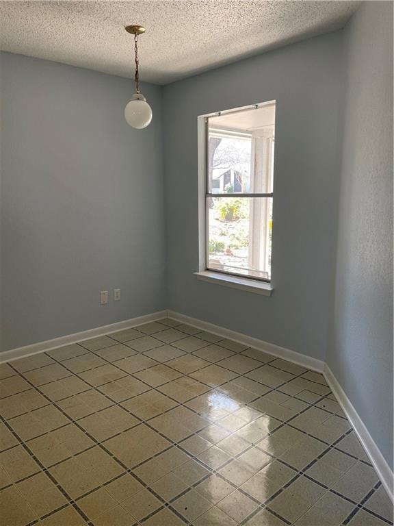 Tiled spare room featuring a textured ceiling and