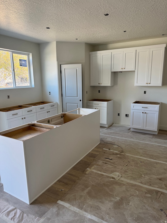 Laundry area featuring a textured ceiling and wood finished floors