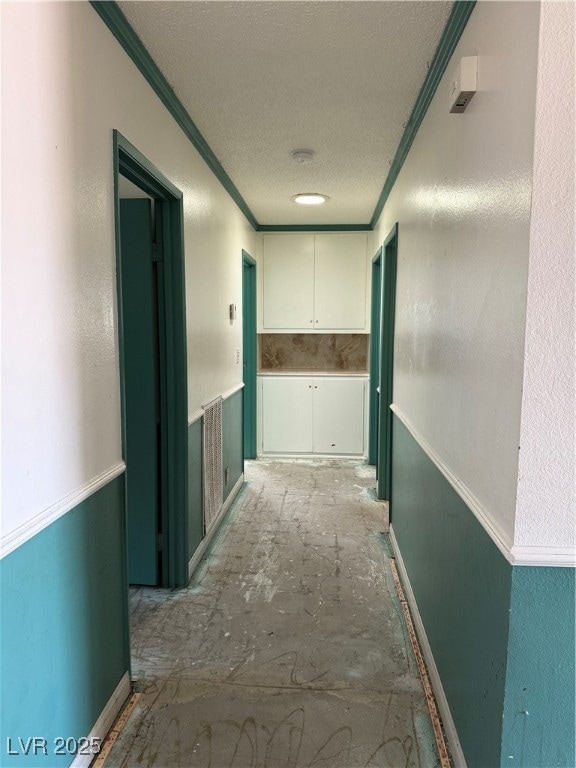 Hallway featuring crown molding and a textured cei
