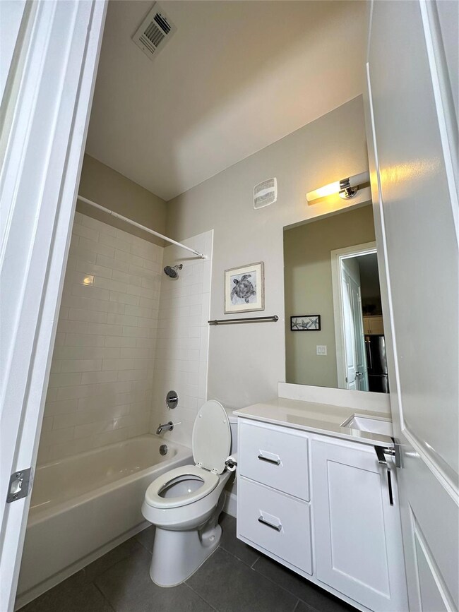 Full bathroom with tiled shower / bath combo, vani