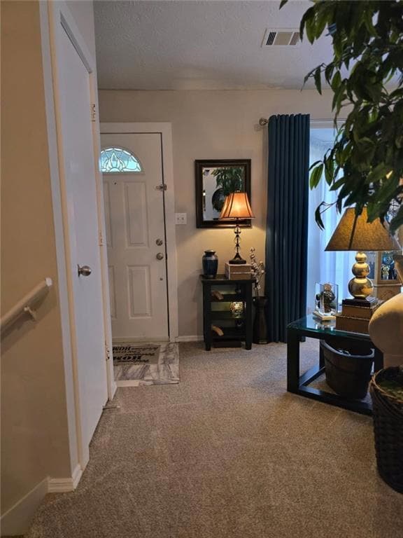 Carpeted foyer with baseboards and a textured ceiling