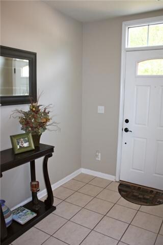 Inviting foyer with tile flooring, fresh paint and half bath with pedestal sink.