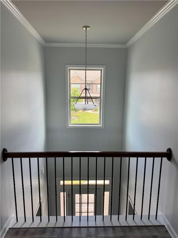 Stairs featuring wood finished floors, a chandelier, ornamental molding, and baseboards