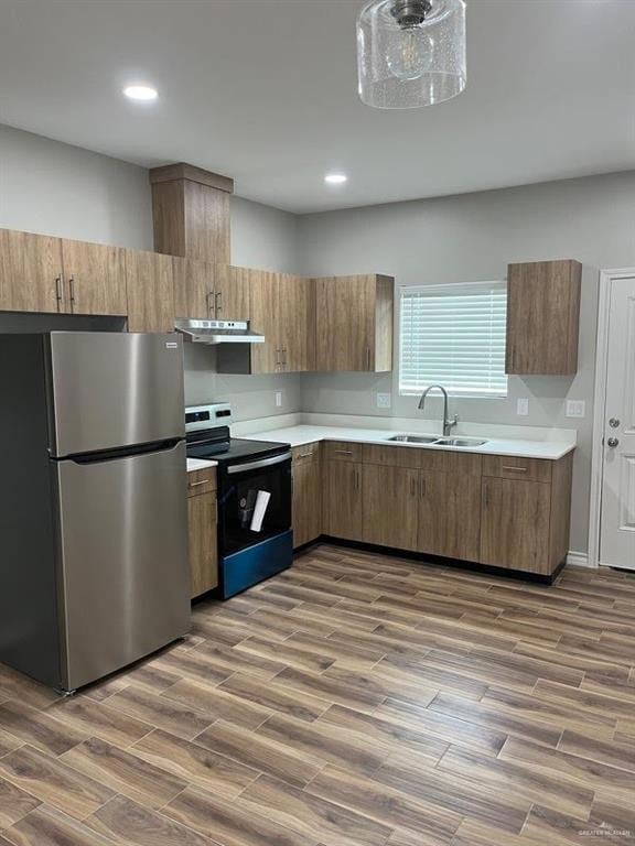 Kitchen with freestanding refrigerator, electric stove, a sink, light countertops, and recessed lighting