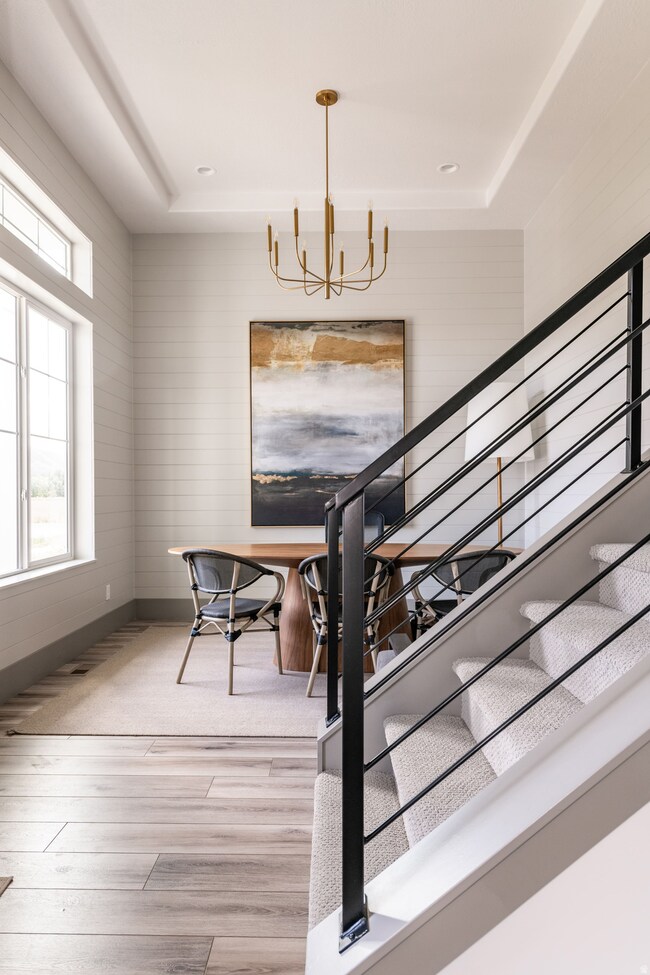 Dining space with stairs, a raised ceiling, light wood-type flooring, a chandelier, and wooden walls