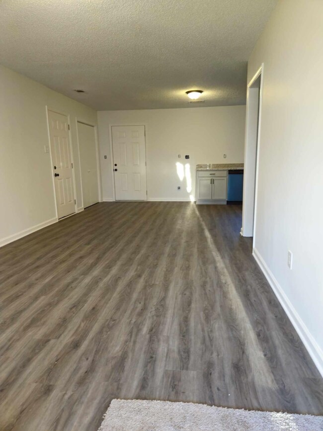 Unfurnished living room featuring dark wood-type f