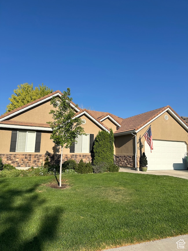 Ranch-style house featuring stone siding, stucco siding, and a front lawn