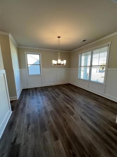 Unfurnished dining area featuring a chandelier, wainscoting, ornamental molding, dark wood-style floors, and healthy amount of natural light