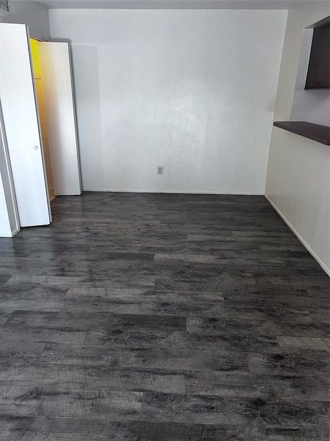 Unfurnished room with dark wood-type flooring and baseboards