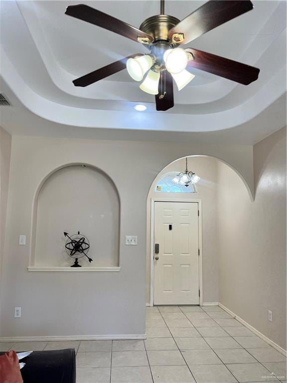 Tiled entryway with a tray ceiling and ceiling fan with notable chandelier