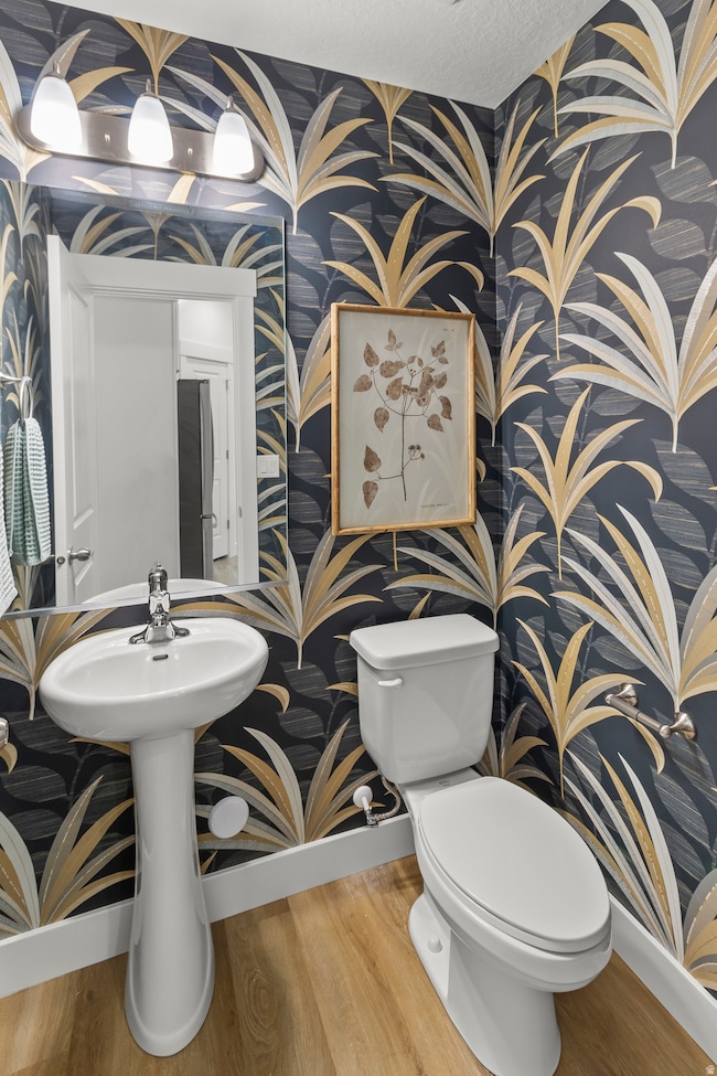 Bathroom with wallpapered walls and wood finished floors