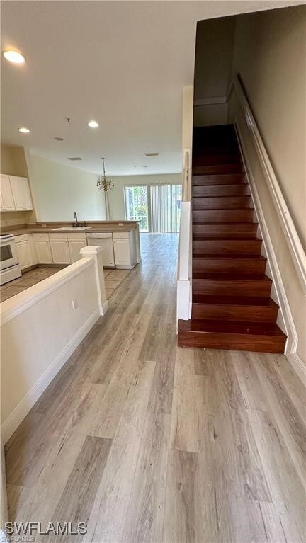 Stairs featuring hardwood / wood-style flooring, an inviting chandelier, and sink