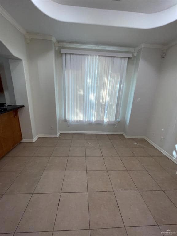 Empty room featuring light tile patterned floors and crown molding