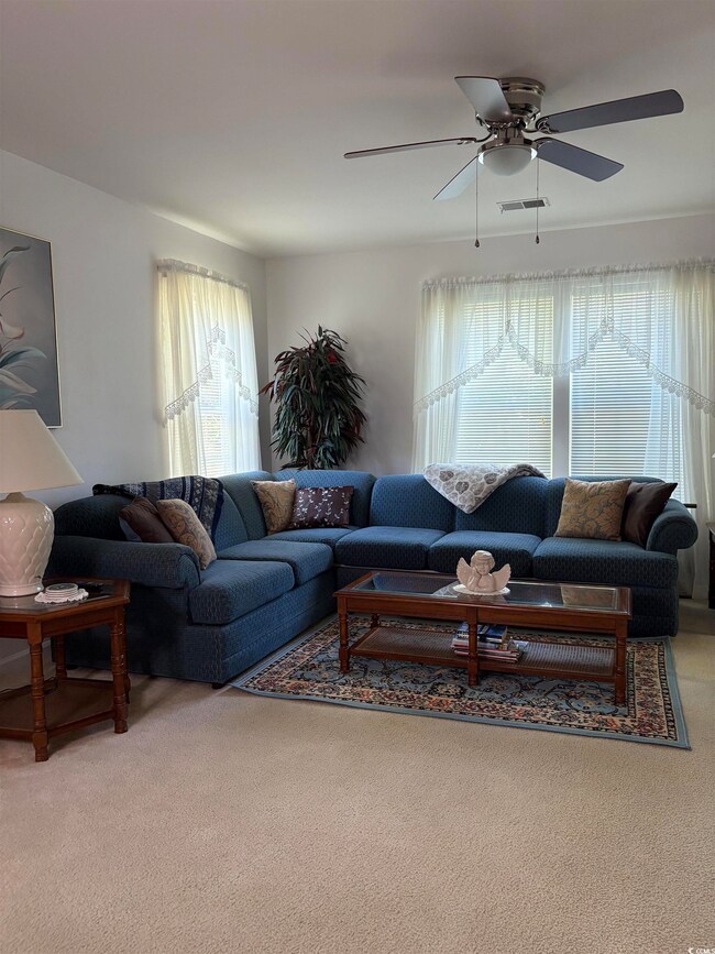 Carpeted living room with a ceiling fan and visibl