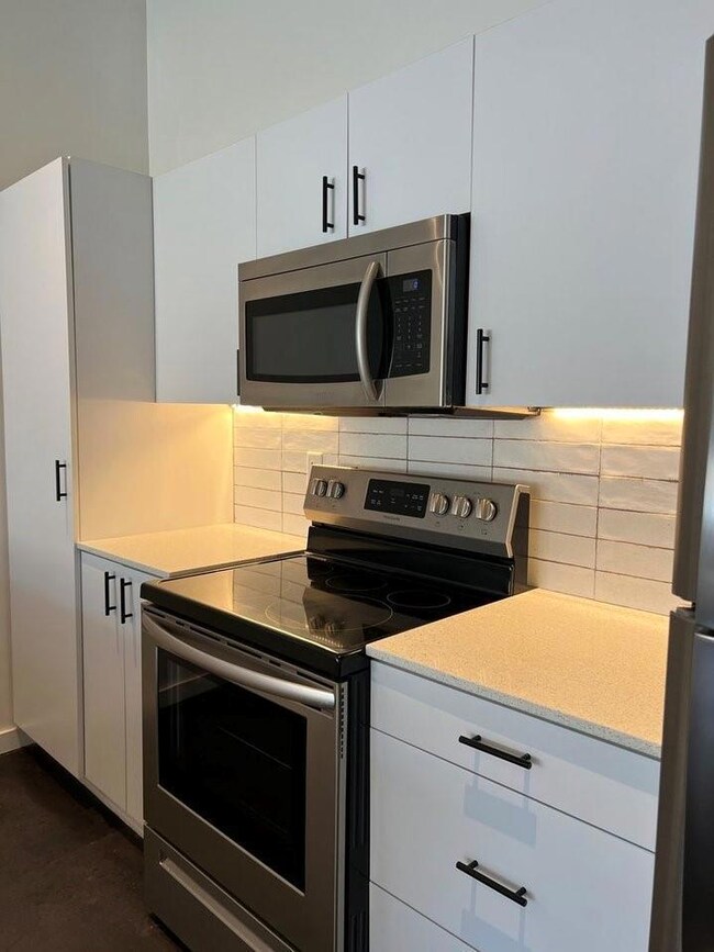 Kitchen with white cabinets, appliances with stain
