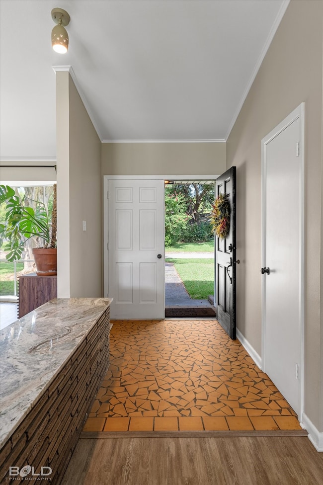 Entryway with wood finished floors and crown molding