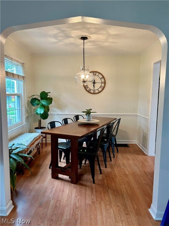 Dining area featuring wood-type flooring, a chandelier, and a textured ceiling