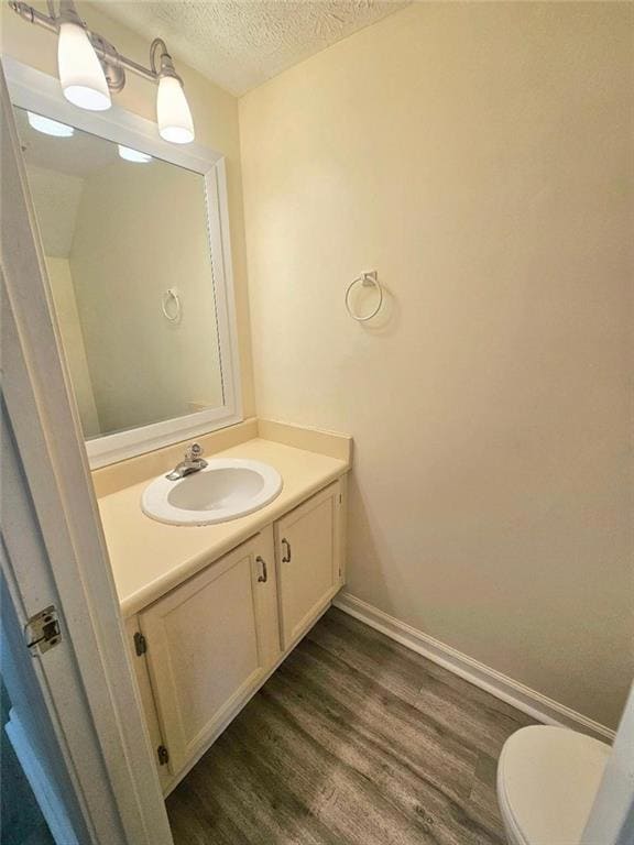 Half bath with a textured ceiling, baseboards, woo