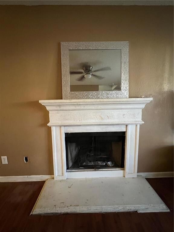 Detailed view of a fireplace, wood finished floors, and ceiling fan