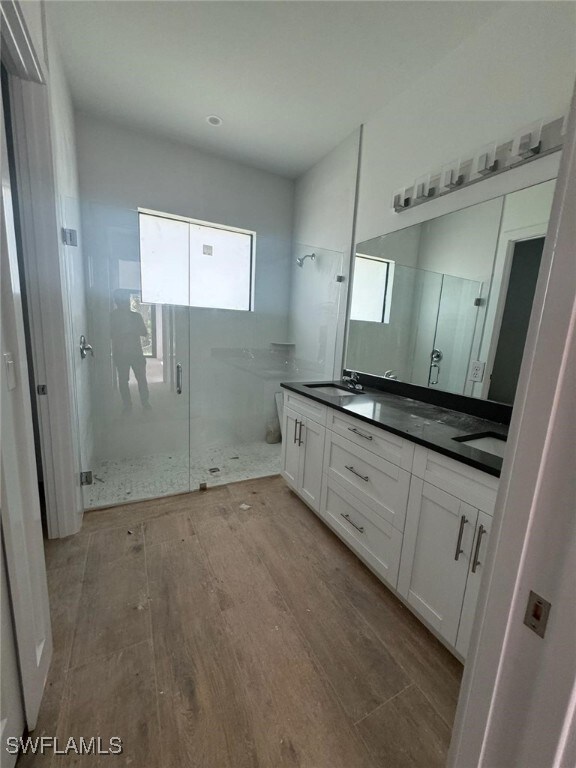 Full bath featuring a sink, double vanity, wood fi