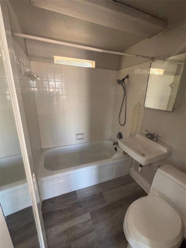 Full bathroom featuring toilet, tiled shower / bath, hardwood / wood-style flooring, and sink