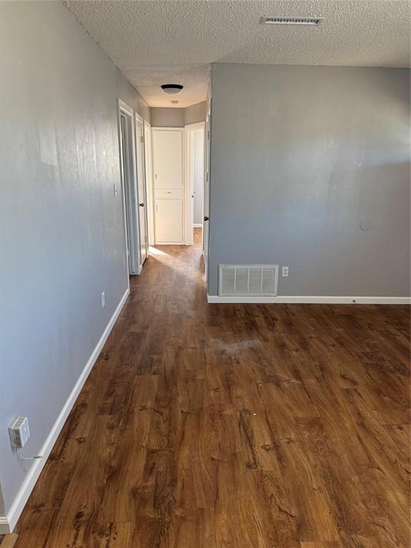 Corridor with a textured ceiling and dark hardwood