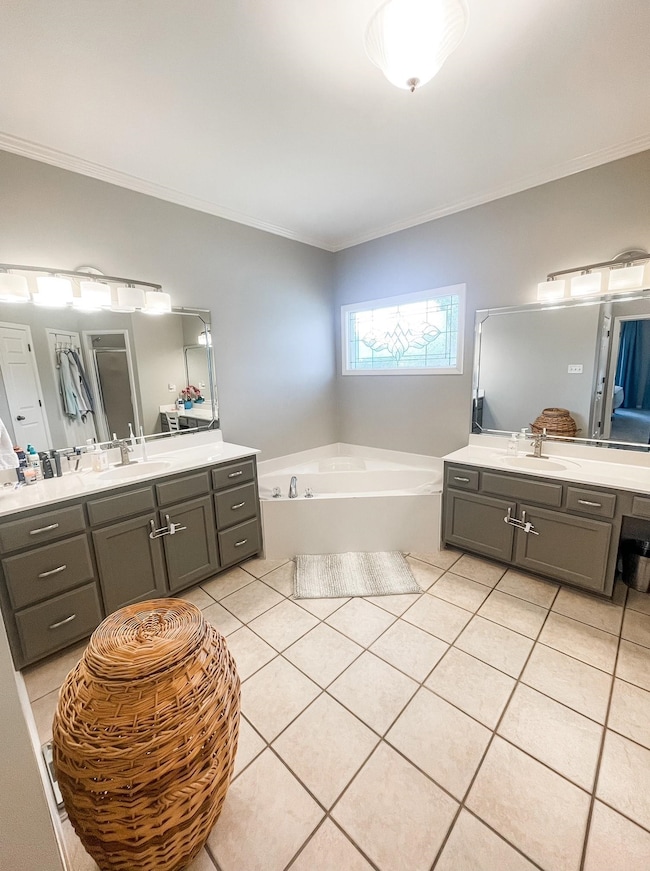 Bathroom with tile patterned floors, a bathing tub, vanity, and ornamental molding