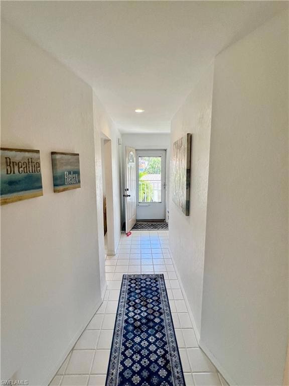 Hallway with light tile patterned floors and baseb