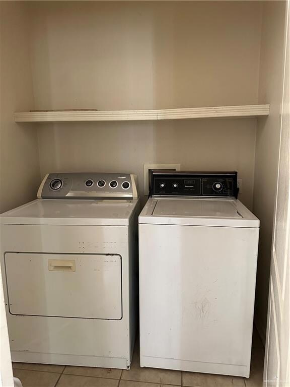 Laundry area with light tile patterned floors and washing machine and dryer