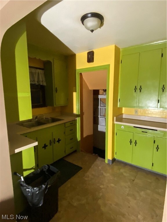 Kitchen with light tile floors, green cabinetry, and sink