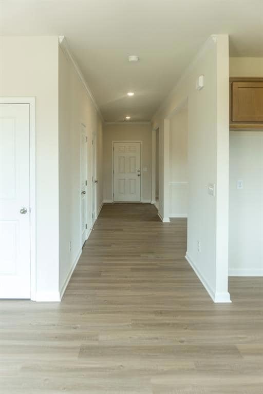 Hallway with ornamental molding, baseboards, light