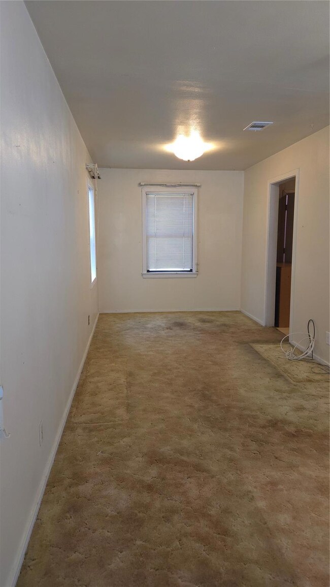 Empty room with visible vents and carpeted floors