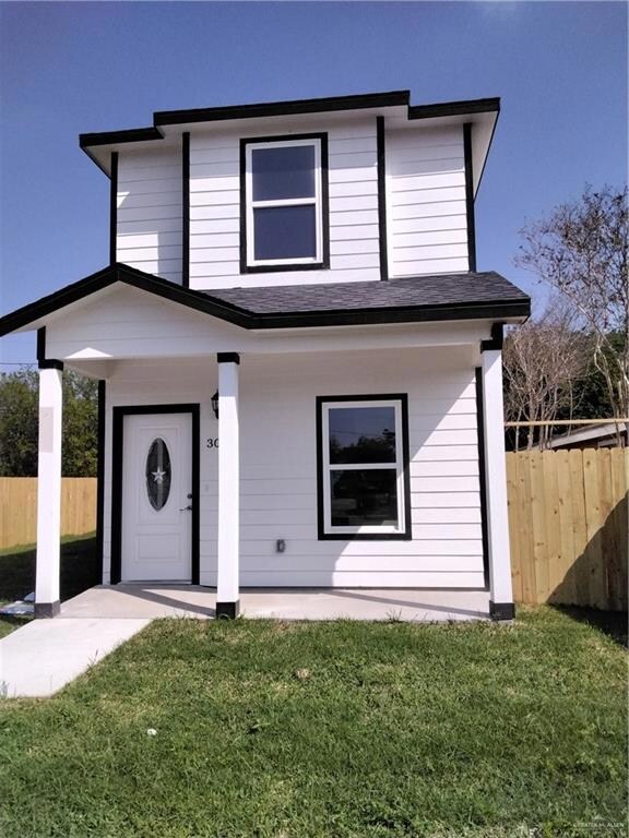 View of front of house featuring fence, roof with shingles, and a front yard