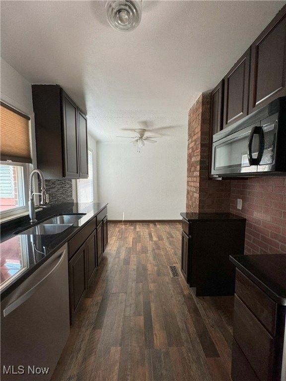 Kitchen featuring ceiling fan, dark brown cabinetry, dark wood-type flooring, appliances with stainless steel finishes, and sink
