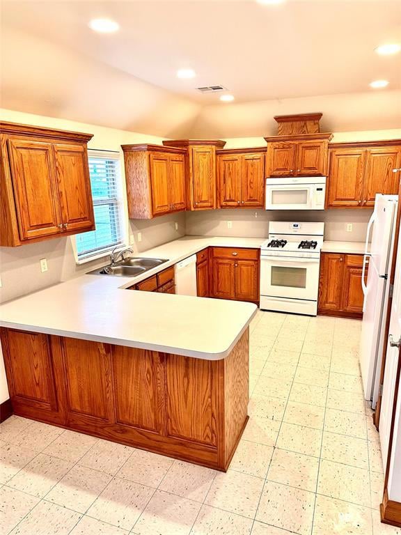 Kitchen with brown cabinetry, a peninsula, white appliances, light countertops, and recessed lighting