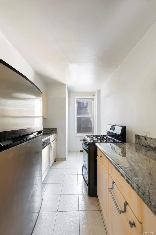 Kitchen with stainless steel appliances, dark stone counters, and light brown cabinetry