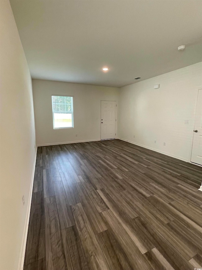 Unfurnished room with dark wood-style floors, recessed lighting, and a smoke detector