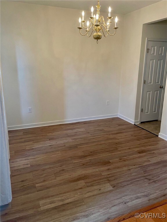 Unfurnished room with dark hardwood / wood-style floors and a chandelier